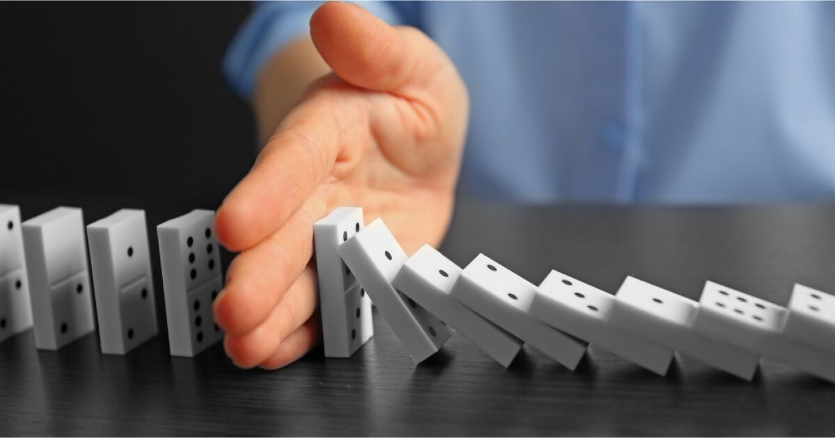 A person stopping a pile of dominoes