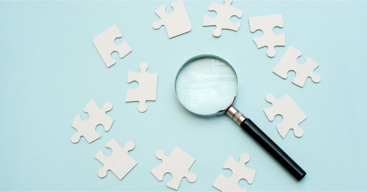 Pieces of puzzle with a magnifying glass