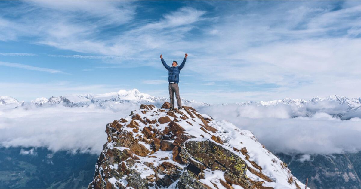 Man celebrating reaching the top of the mountain