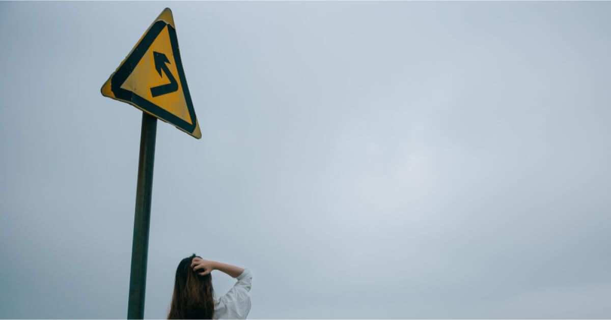 A woman standing before a direction sign