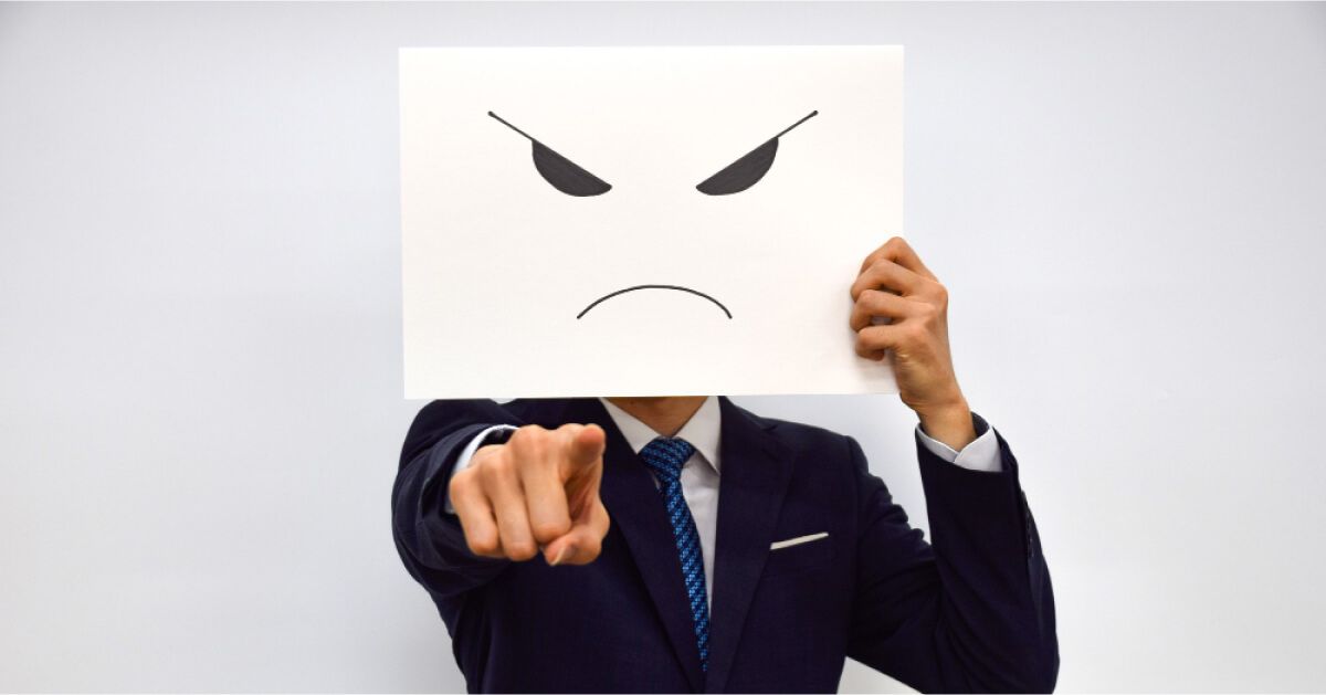 A man covering his face with an emoji drawn on a paper