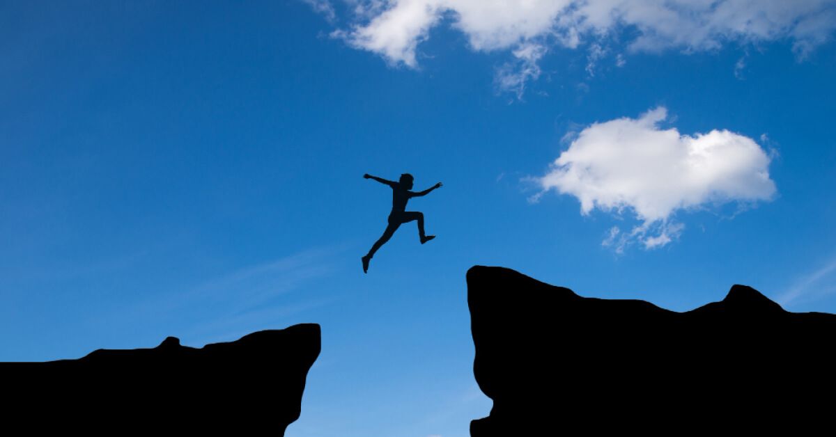 A man jumping onto another mountain