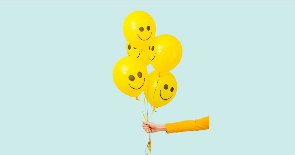 A person holding balloons with smiley face