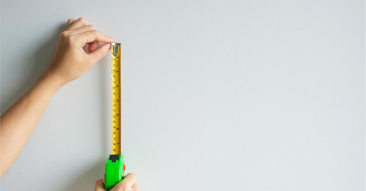 A woman measuring the wall