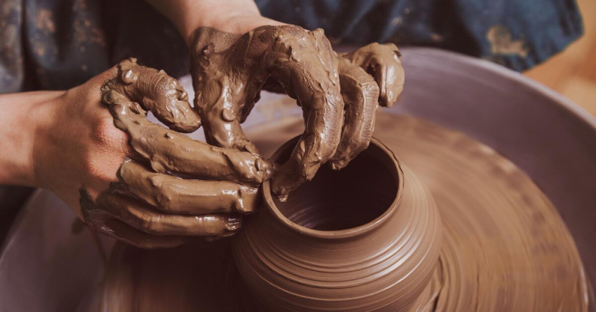 A person is crafting a clay pot 