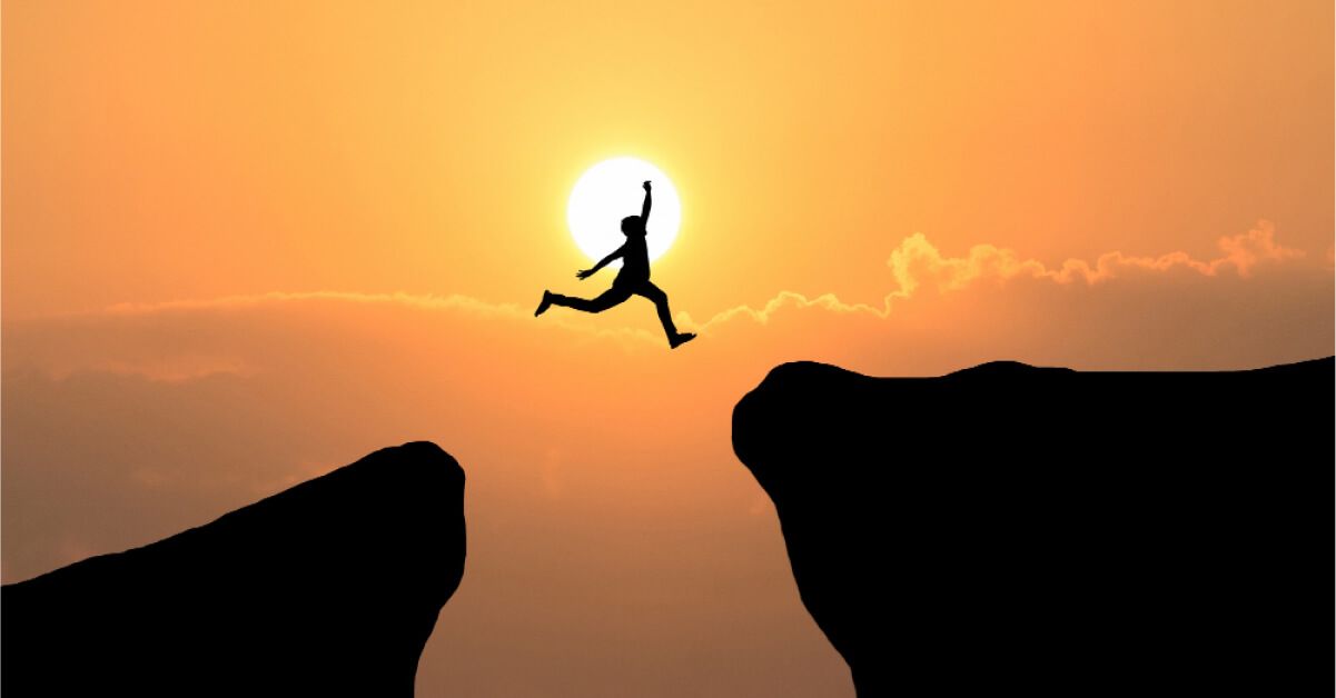 A man jumping from one cliff to another