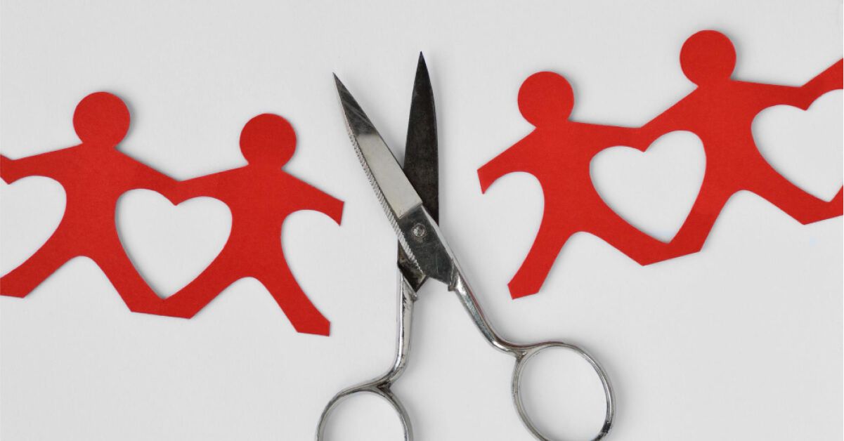 A scissors cutting paper cutouts of men