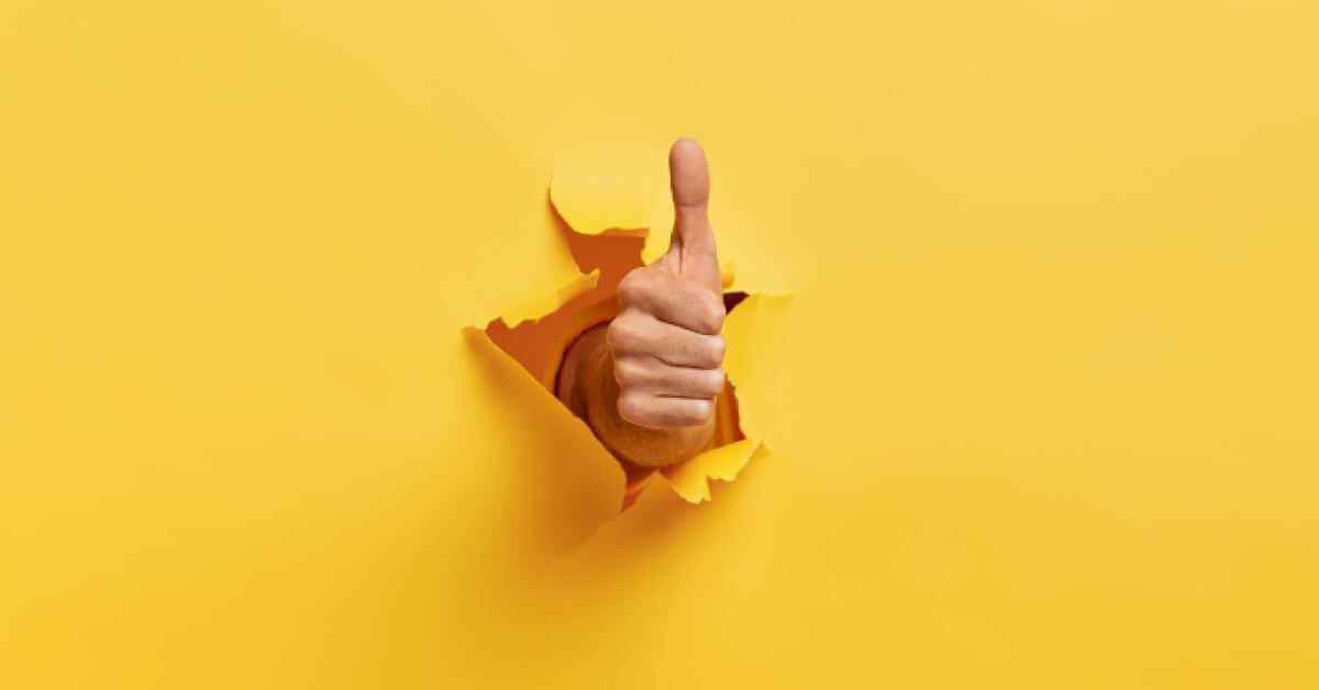 A thumbs up through a yellow wall 