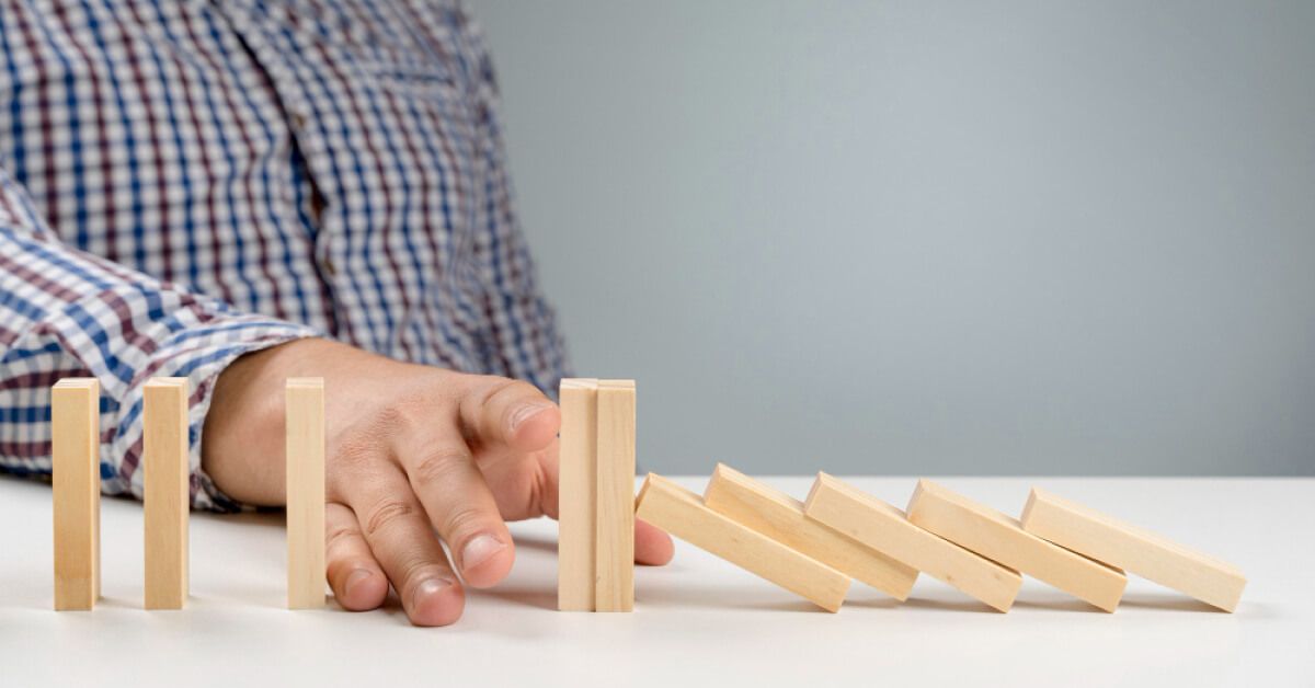 Person stopping a wooden block from falling over