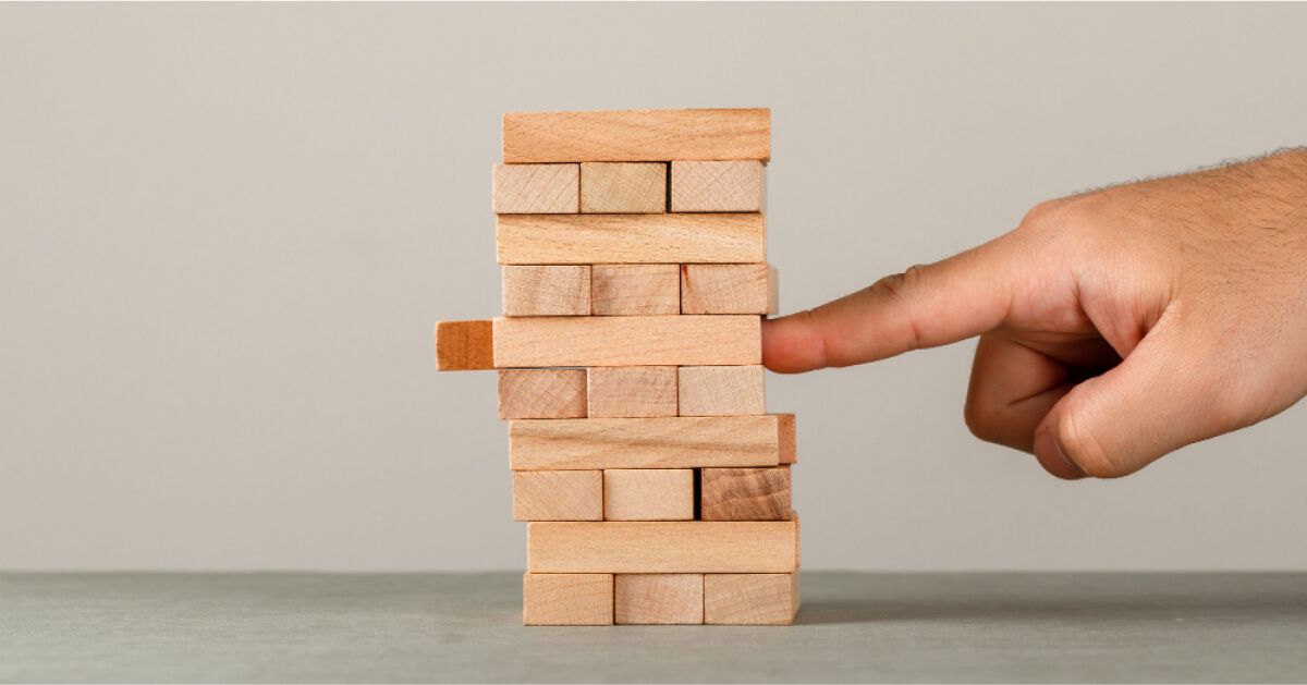 Someone pushing a single wooden block out of an organized jenga structure