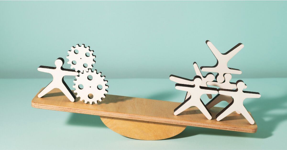 A cardboard seesaw with cardboard cutouts of people & gears