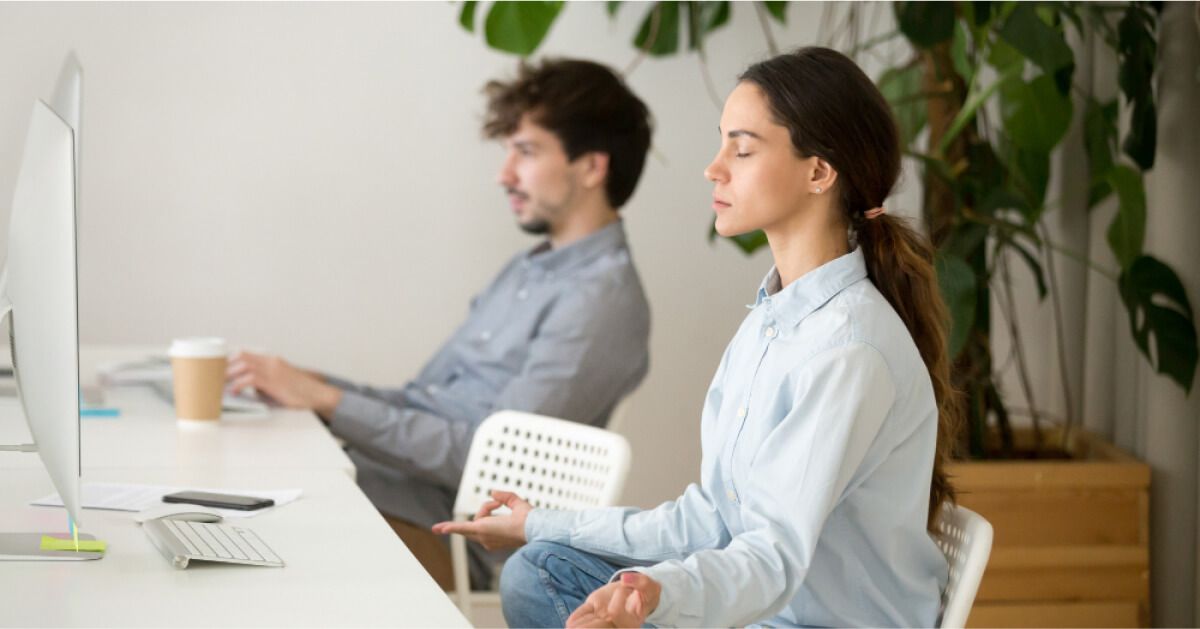 Person sitting in a meditative pose in front of a desktop screen