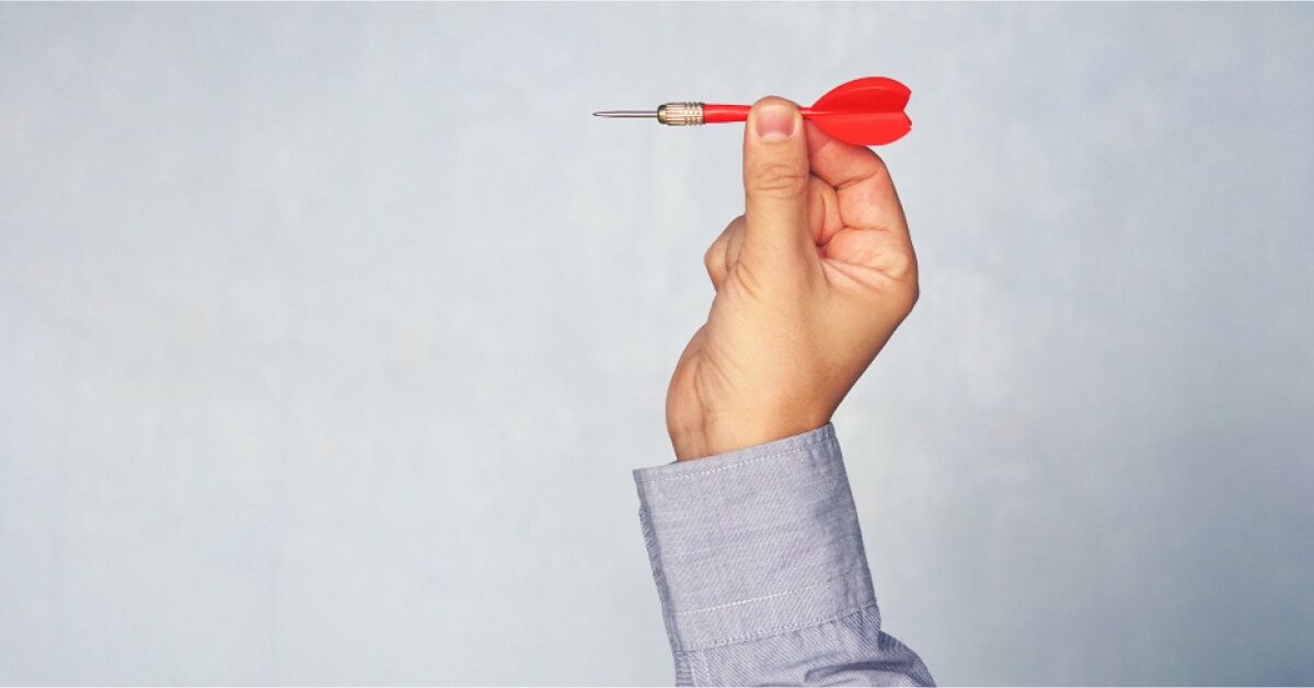 Person aiming to throw a red dart