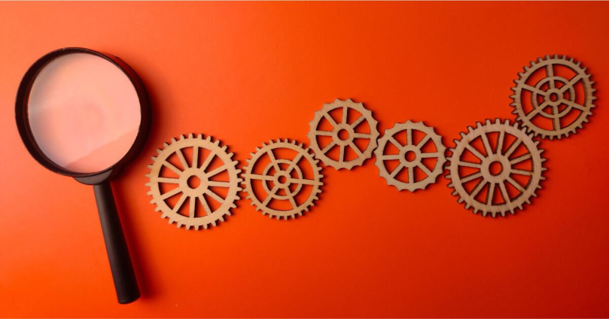 A magnifier glass placed next to a set of interlinking gears