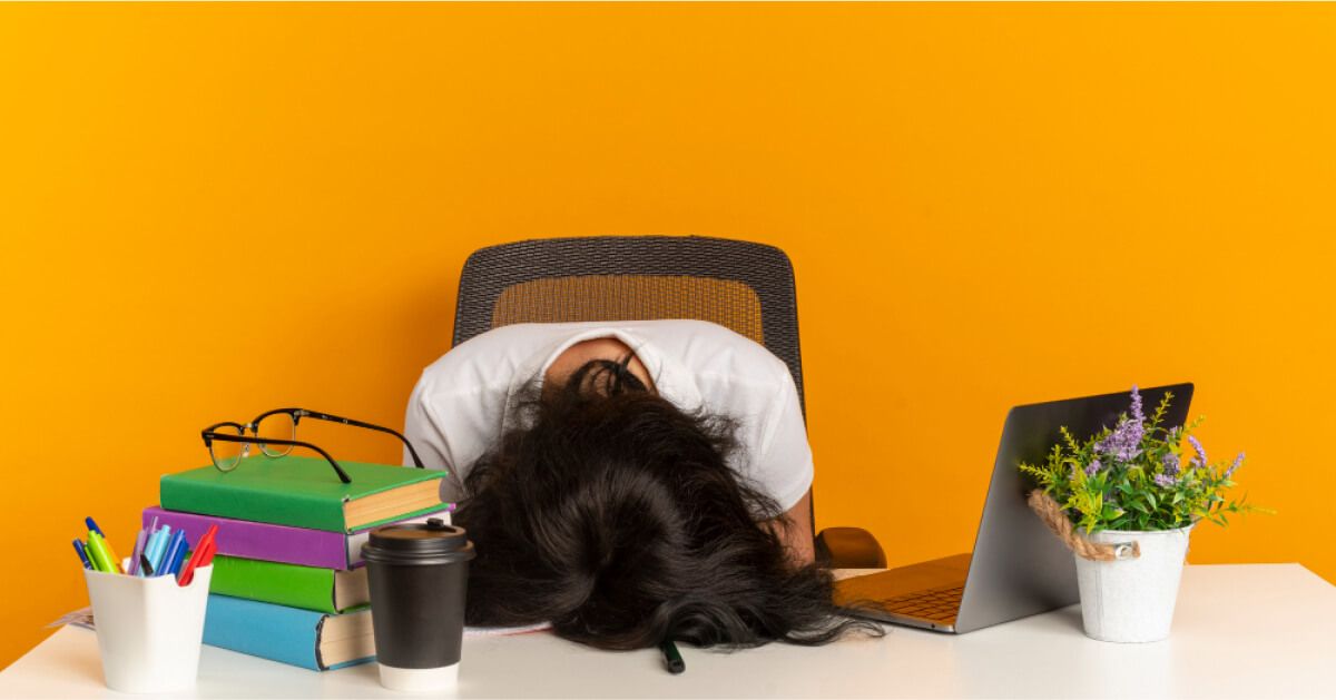 Person being visibly tired in front of a laptop, with their head against the table