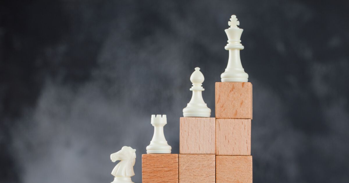 Different chess pieces placed on top of wooden blocks that are arranged like steps