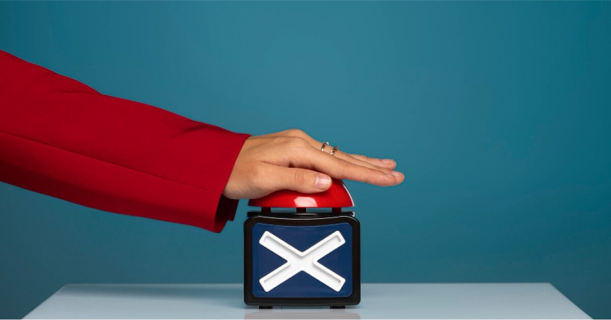 A hand with red sleeve pushing red buzzer.