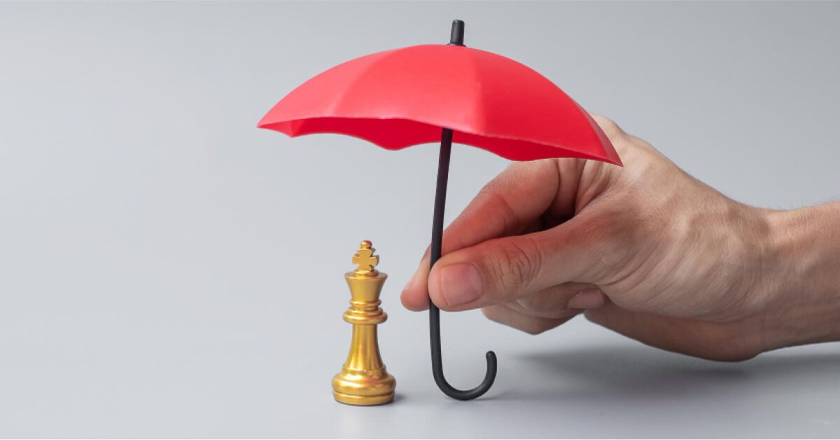 A red umbrella giving shade to chess pawn