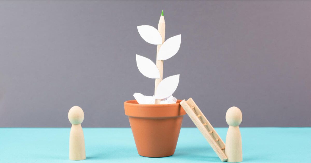 Two wooden pawns and a ladder next to a dummy potted plant