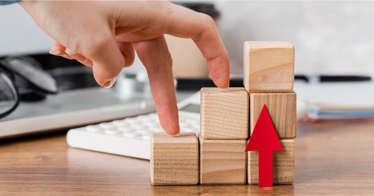 Wooden blocks arranged in a step wise manner with an upward red arrow next to it