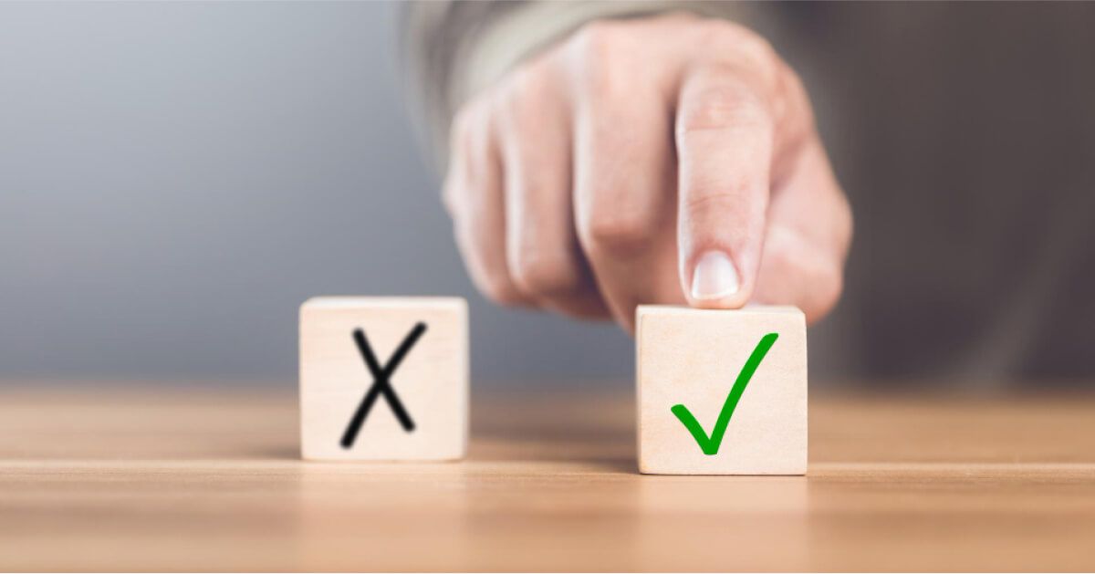 A hand choosing a wooden block that has green tick mark.