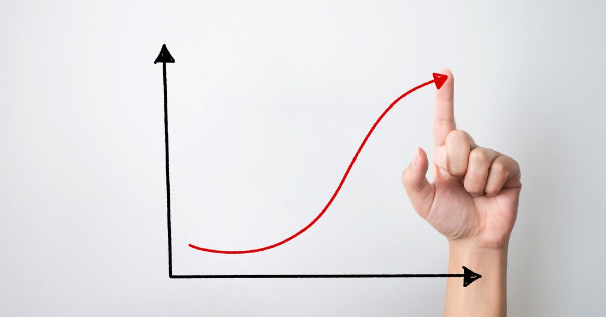 Person pointing at an upward red arrow in a graph