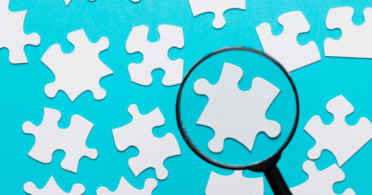 White puzzle pieces viewed with a magnifier glass