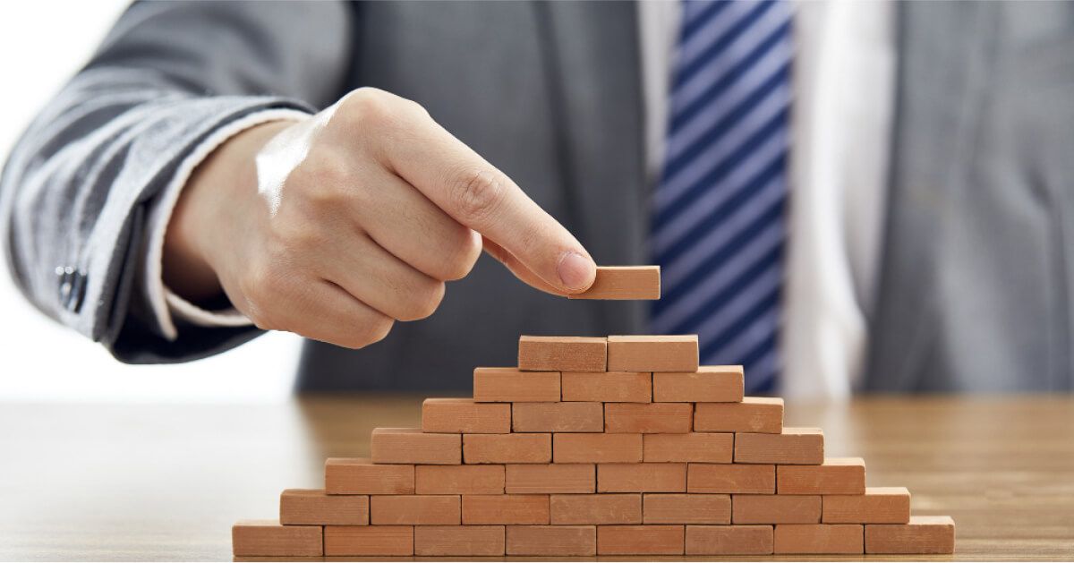 A man stacking wooden blocks in a pyramid shape.