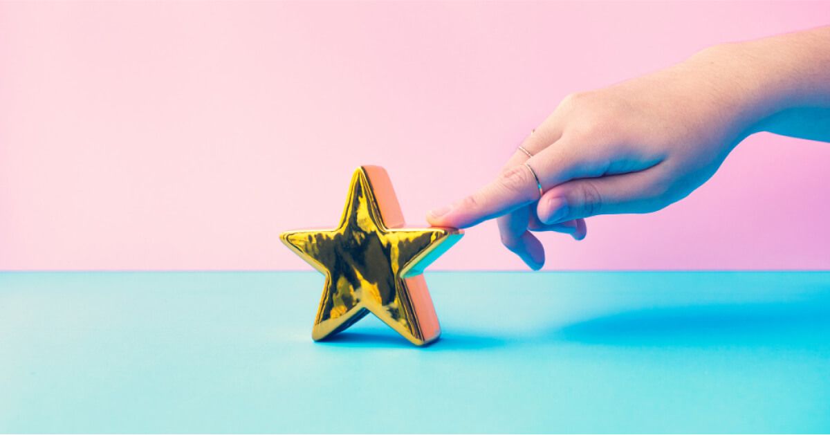 Person touching a golden star against a vibrant colored backdrop