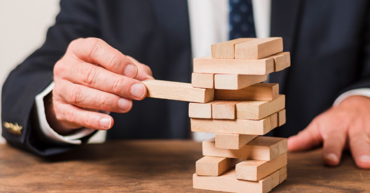 Person wearing a suit interacting with a Jenga tower