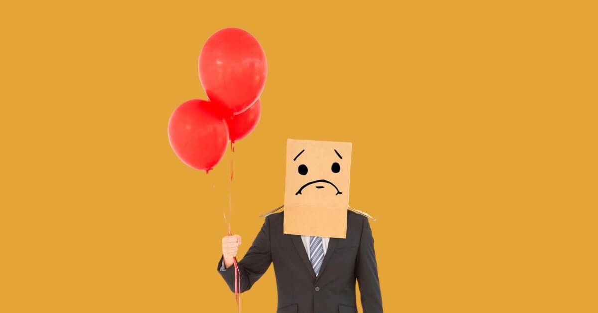 Person holding red balloons, with a sad cardboard box over their head