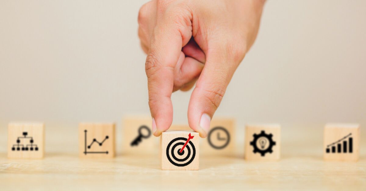 Person holding a wooden block with a target symbol on it