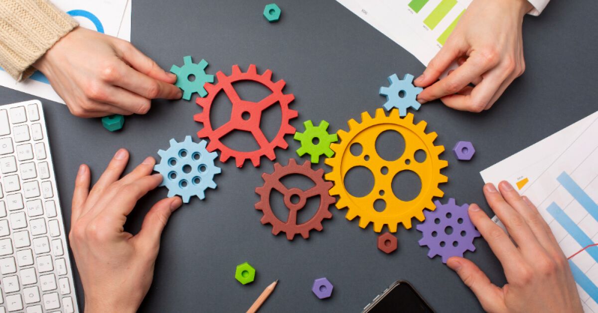 People sitting together and arranging multicolored gears over the table