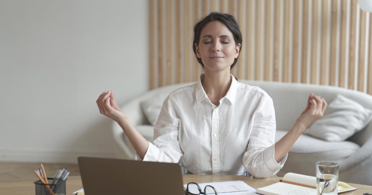 Woman in a meditative pose in front of a laptop screen