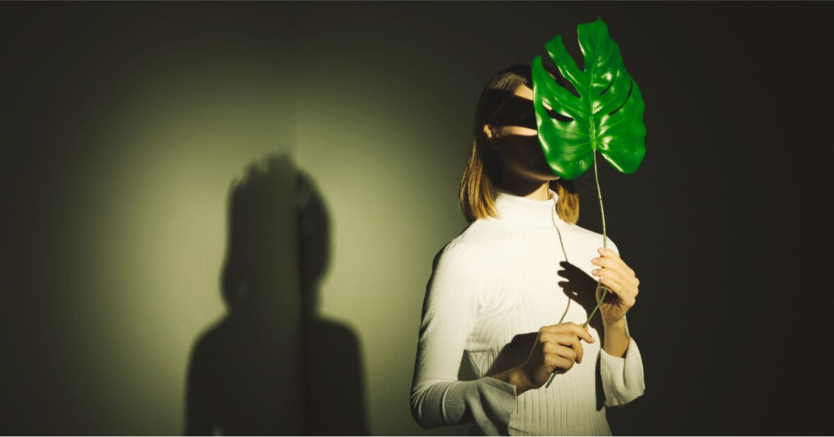 A person holding green leaf in her face.