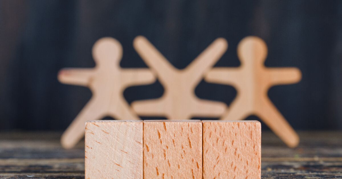 Wooden pawns behind three wooden blocks