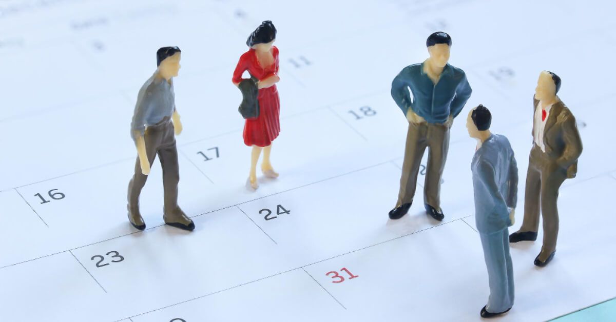 Miniature figurines in discussion over a calendar