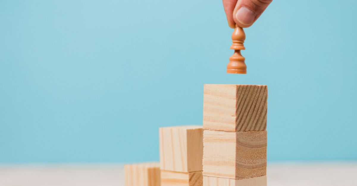 Person placing a chess piece on a set of wooden blocks