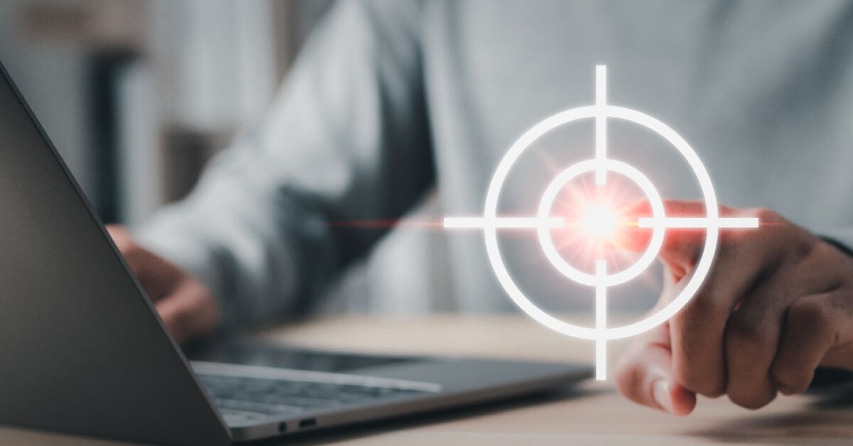 Someone pointing the finger at a graphic target while working on their laptop