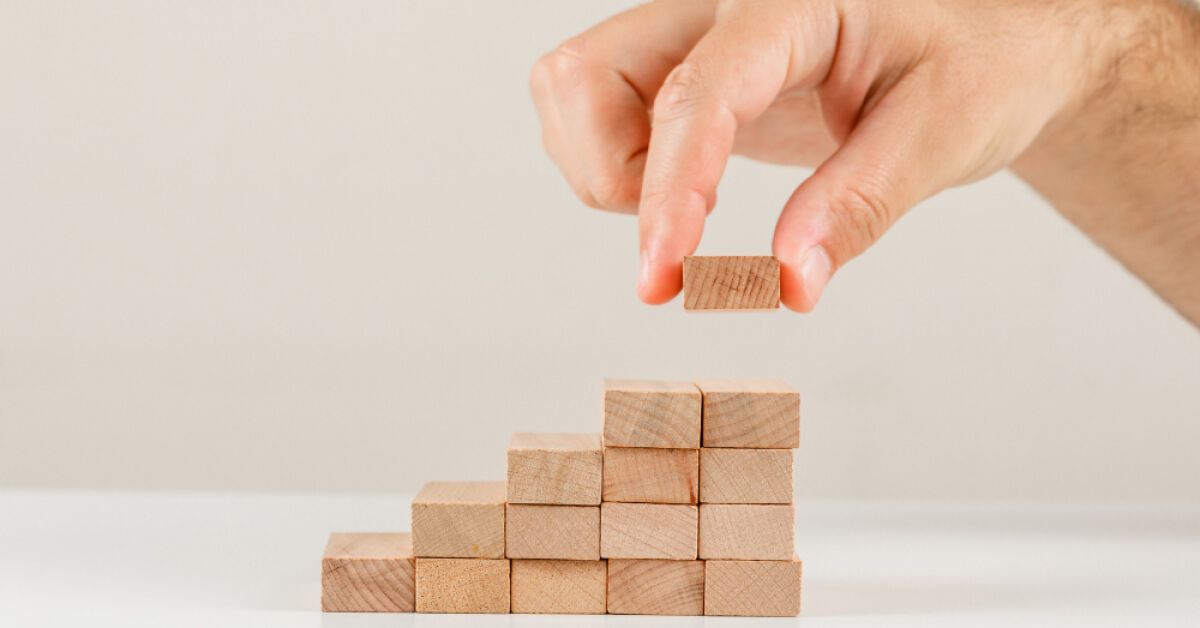 A hand stacking wooden blocks