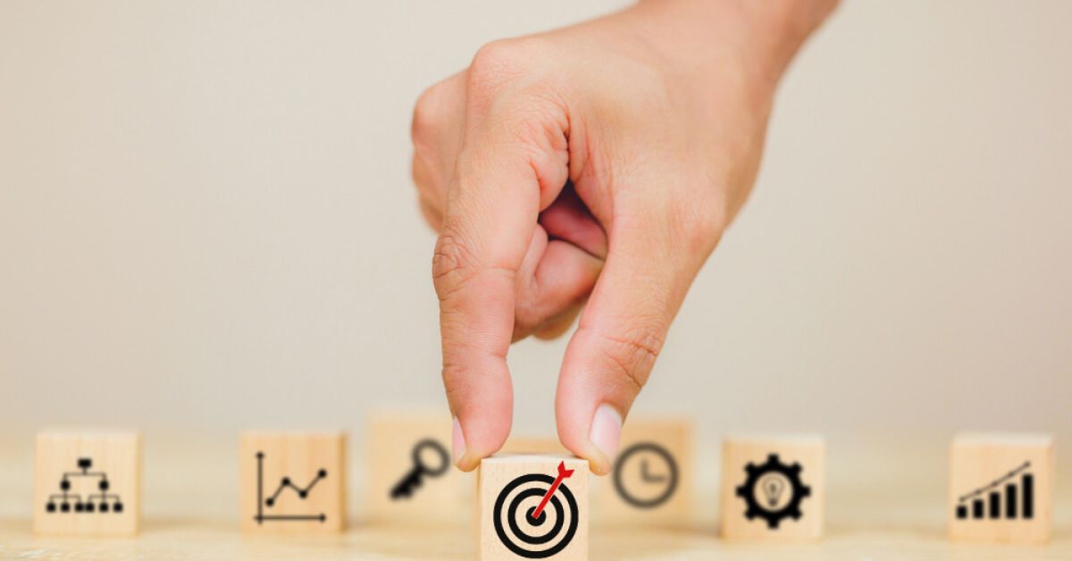 Person holding a wooden block with a target graphic on it, surrounded by other wooden blocks with similar graphics