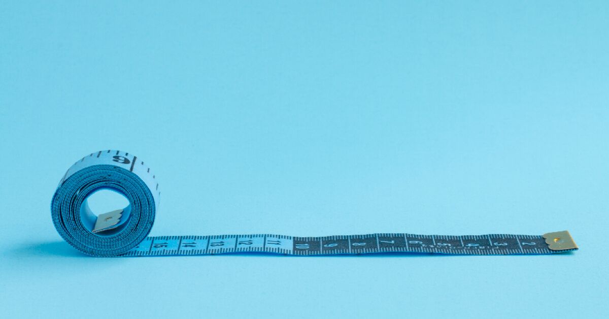 Blue measuring tape against a blue backdrop