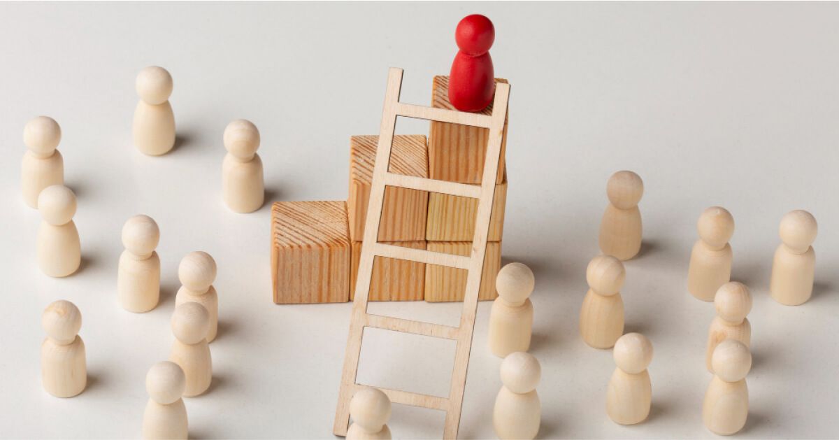 A red pawn climbing a ladder to the top while a group of other wooden pawns are underneath