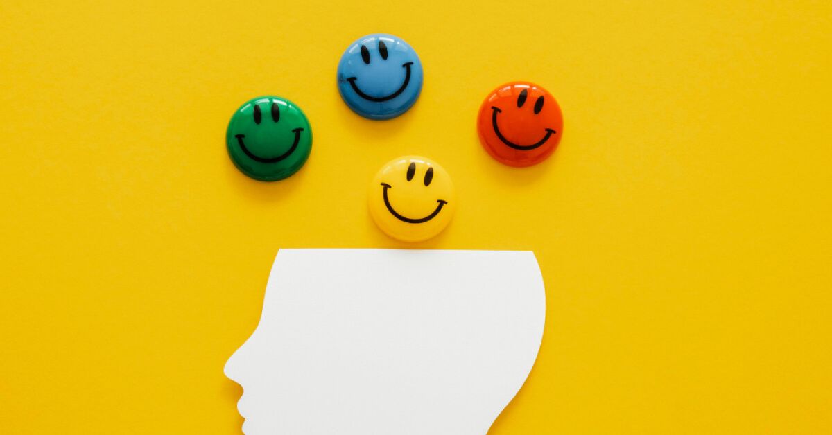 Multicolored smiley pins over a paper cutout of an open human head