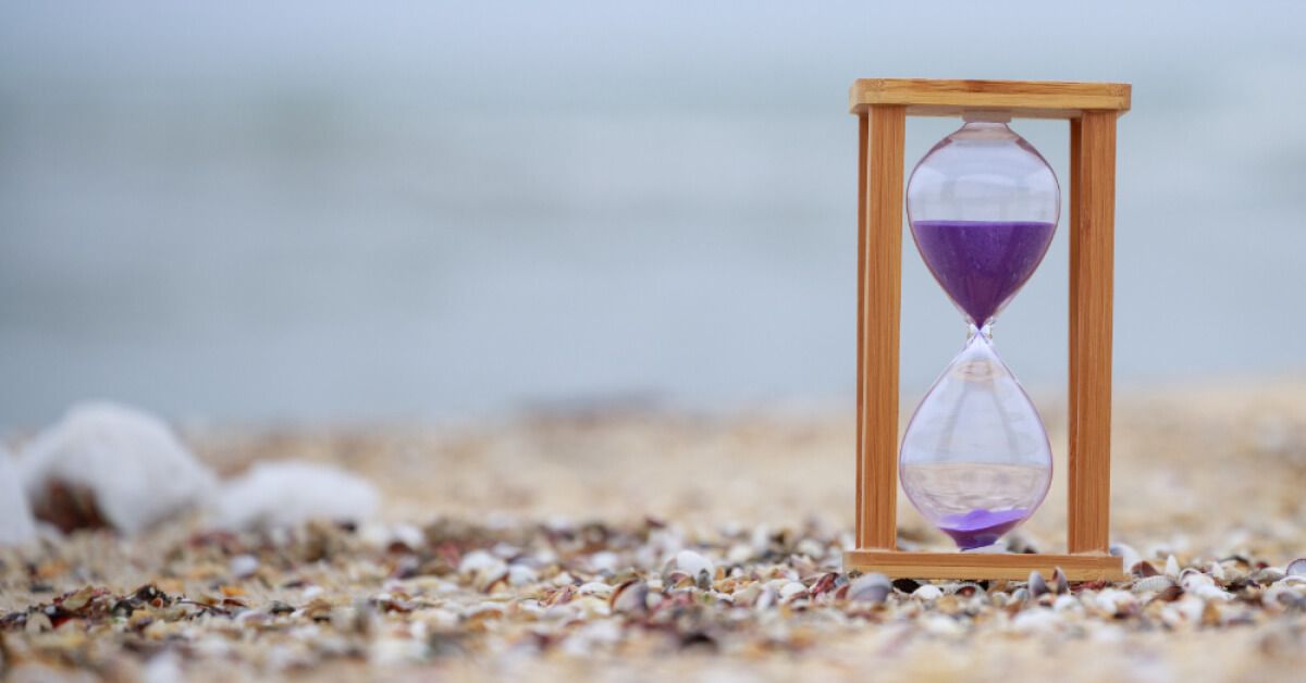 Hourglass with purple sand, on the beach