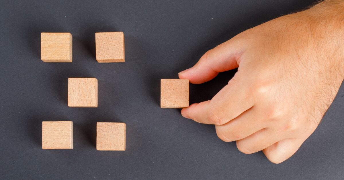 Person holding a wooden block away from a group of wooden blocks