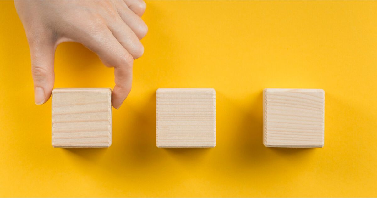 A man arranging three wooden blocks