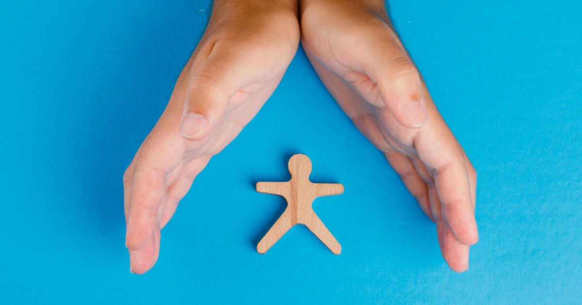 Hands protecting a small wooden pawn