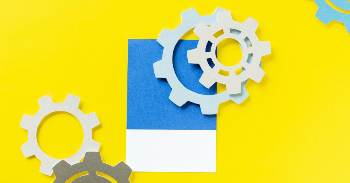 Paper cutouts of gears against a yellow backdrop