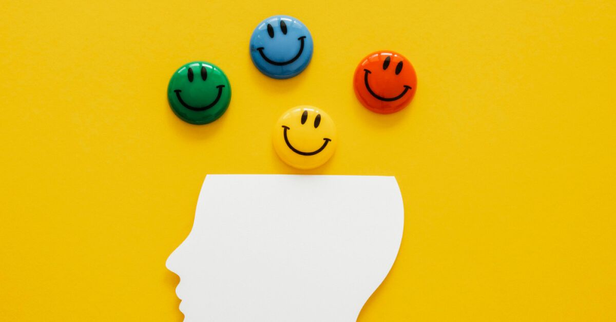 Multicoloured smiley faces on top of a white cutout of a head